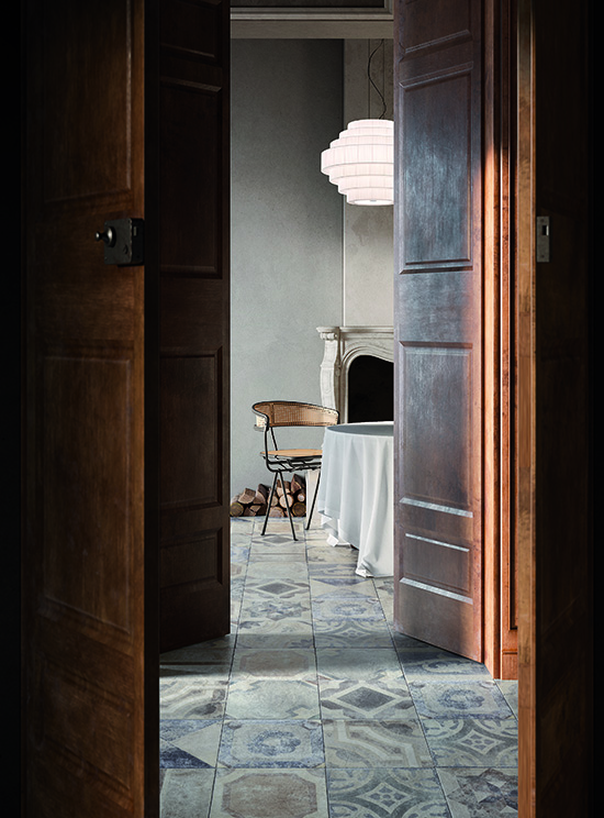 entrée de salon campagne, recouverte de carrelage à motifs, avec un mobilier de bois brut, le tout dans une décoration très épurée aux murs beige.
